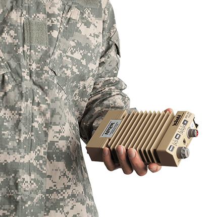 Close up of a person in an army uniform holding a tan IPS-250X Ethernet Encryptor