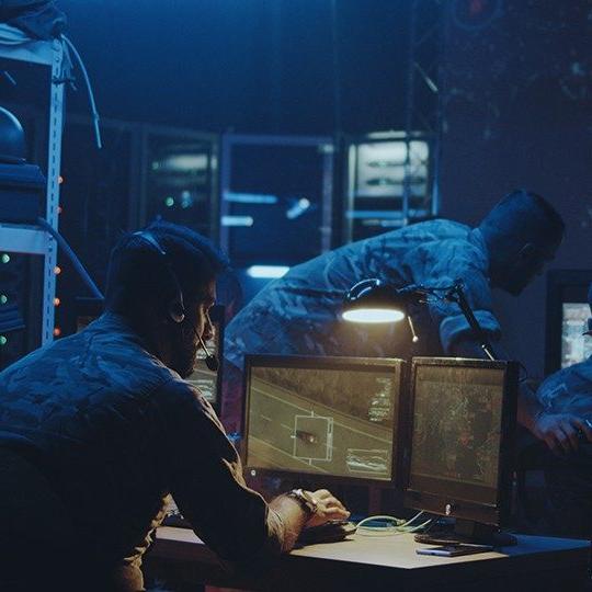 3 men in a room using a tactical communications to monitor a mission